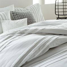 an unmade bed with white sheets and pillows