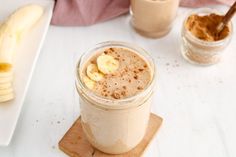 there is a banana smoothie in a glass next to two bananas on a cutting board