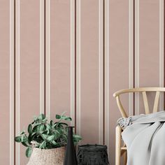 a wooden chair sitting next to a potted plant on top of a table in front of a pink wall