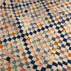 an old quilt is laying on top of a bed sheet that has been made into a checkerboard pattern