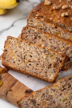 sliced loaf of banana nut bread sitting on top of a cutting board next to bananas