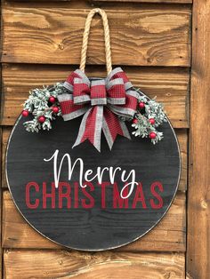 a merry christmas sign hanging on the side of a wooden wall with a bow and holly wreath