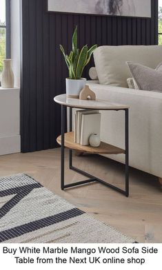 a white sofa sitting next to a table on top of a rug in a living room