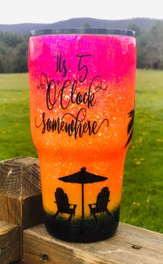 a pink and orange tumbler with black writing on it that says it's 5 o'clock somewhere