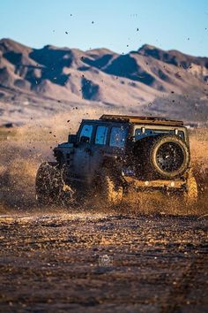 a jeep driving through the desert with mountains in the background