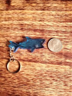 a keychain with a shark on it and a coin sitting next to it