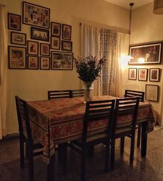 a dining room table and chairs in front of pictures on the wall with flowers inside