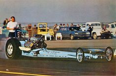 a drag car with the front wheel spinning on its side at a race track while people watch