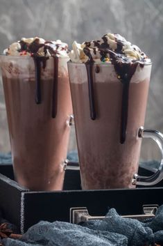 two chocolate milkshakes with whipped cream and chocolate drizzle