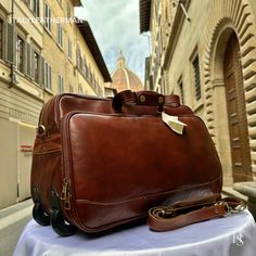 This Italian leather travel bag is expertly handcrafted in Florence, Italy, using the finest genuine leather. Designed for men seeking premium quality, luxury, and modern Italian fashion, this duffle bag with wheels allows you to travel with ease and sophistication. . Size: Height: 33 cm (12.99 inches) Width: 50 cm (19.69 inches) Depth: 24 cm (9.45 inches) . The story of this travel bag: In the heart of Italy, where the rich legacy of craftsmanship thrives, there existed a renowned workshop dedicated to creating exquisite travel accessories. Among their coveted collection were the handmade duffle bags, carefully crafted to cater to the needs of discerning travelers seeking both style and functionality. These duffle bags, designed specifically as men's travel gear, embodied the essence of I Luxury Cognac Briefcase For Travel, Luxury Cognac Briefcase With Luggage Sleeve, Luxury Cognac Travel Bag, Luxury Cognac Travel Bag For Overnight Trips, Luxury Cognac Travel Bag For Business Trips, Elegant Leather Bag For Trips, Luxury Brown Briefcase For Overnight Trips, Elegant Brown Travel Bag For Trips, Formal Brown Travel Bag With Leather Lining