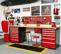 a garage with lots of tools on the wall and red cabinets in front of it