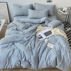 an unmade bed with blue and white checkered comforter, pillows and blankets