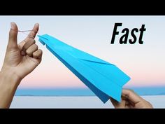 a hand holding up a blue paper airplane with the word fast written on it in front of