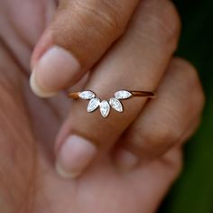 a woman's hand holding a gold ring with two small leaves on the side