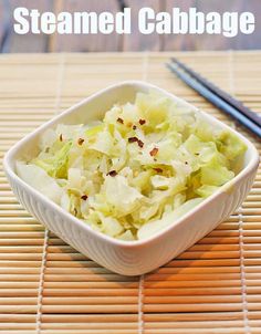 a white bowl filled with food next to chopsticks on top of a table