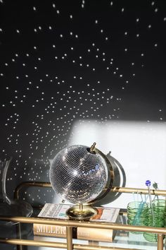 a mirror ball sitting on top of a table next to a vase and glass bottles