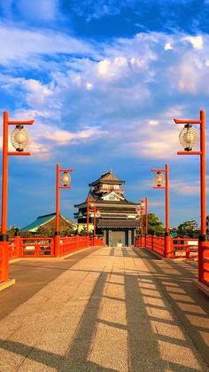 an orange bridge with lanterns on each side and a clock tower in the back ground