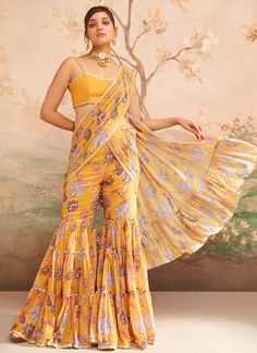 Mustard Yellow Floral Printed Pant Saree includes a georgette blouse and georgette with santoon inner saree. Embroidery is present on this style using thread, stone, print, zari, and hand work. Like all of our pieces, this piece is made in India and checked by hand to ensure high quality. Designer Georgette Lehenga With Printed Motifs, Festive Georgette Lehenga With Printed Motifs, Georgette Pre-draped Saree With Dupatta For Diwali, Festival Georgette Lehenga With Printed Motifs, Georgette Sharara With Sheer Dupatta For Diwali, Transitional Pre-draped Saree With Dupatta In Georgette, Bollywood Style Pre-draped Georgette Saree For Diwali, Transitional Pre-draped Georgette Saree With Dupatta, Yellow Palazzo Set With Printed Motifs In Traditional Drape