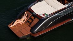 a woman is lounging on the deck of a small boat that's floating in the water