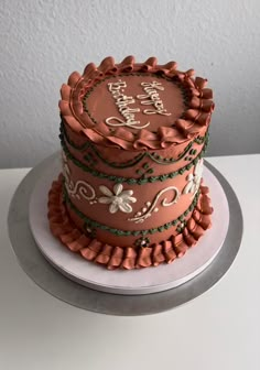 a three tiered birthday cake decorated with flowers and ribbons on a white table top