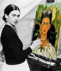 a woman holding a brush in front of an easel with a painting on it