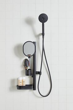 there is a shower head and mirror on the wall next to it's holder