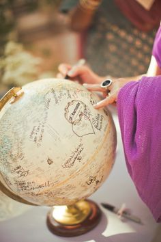 a woman is writing on an old globe