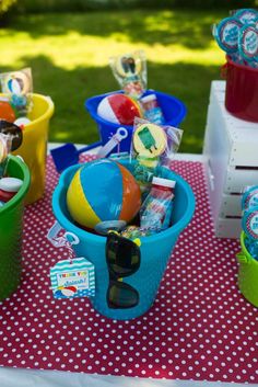 colorful beach balls and sunglasses are in buckets on a table