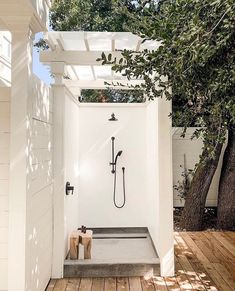 an outdoor shower in the middle of a wooden floored area with white walls and wood floors