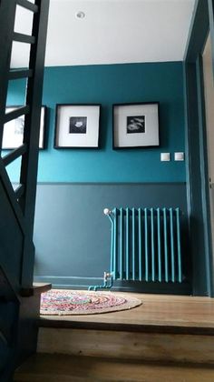 a room with blue walls and pictures on the wall next to a stair case in front of a window