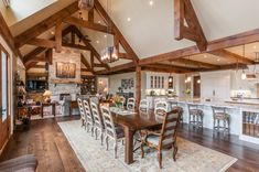 a large open concept kitchen and dining room with wood beams on the ceiling, hardwood flooring