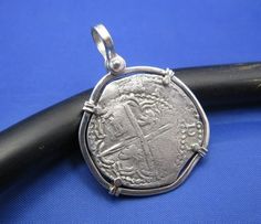 an old silver coin sitting on top of a black piece of metal next to a blue background