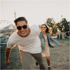 a man and woman are playing frisbee in the grass at an amusement park