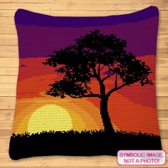 a crocheted pillow with a tree and sunset in the background