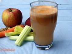 an apple, carrots and celery are next to a glass of drink