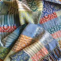 a multicolored knitted blanket laying on top of a wooden table