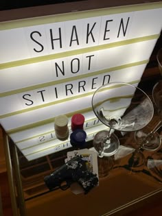 there is a sign that says shaken not stirred and some wine glasses next to it