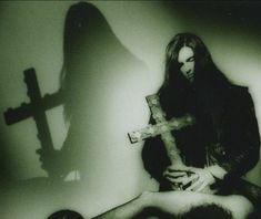 a man holding a cross in front of a person laying on the ground with their hands