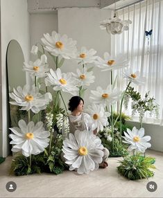 a woman sitting on the ground surrounded by fake flowers