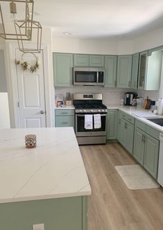 a kitchen with green cabinets and white counter tops