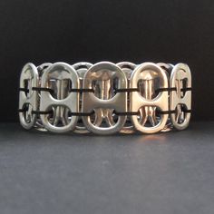 a close up of a metal bracelet on a black surface with an oval design in the middle