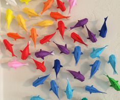 colorful origami fish are arranged on a white wall and placed in the shape of a circle