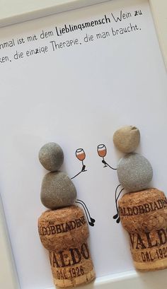 two wine glasses sitting on top of rocks in front of a sign that says,