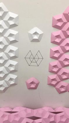 pink and white origami shapes are arranged on the wall