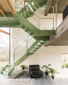 a living room with a black chair and green stairs