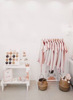 a room with white walls and pink shirts hanging on the rack in front of it