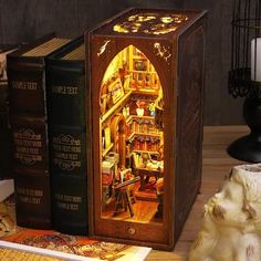 an illuminated book case sitting on top of a wooden table next to books and a lamp