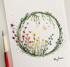 a watercolor painting of flowers in a circle on paper next to a red pen