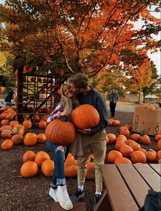 two people are hugging each other in front of pumpkins on display at the park