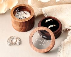 two wedding rings in wooden boxes next to a ring box with the name mr and mrs written on it